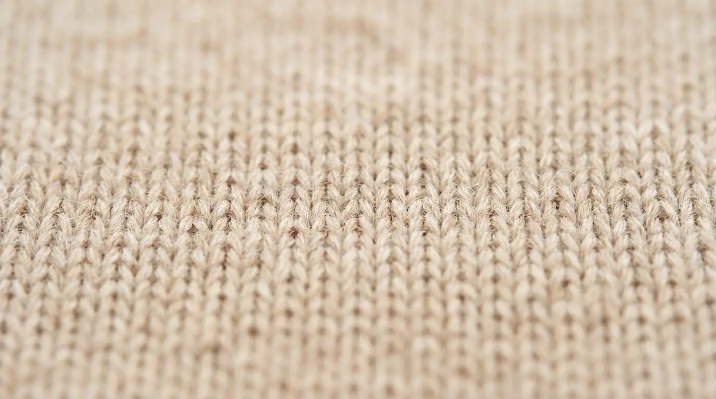 Détail gros plan d'un tricot maille fine, point régulier, fibres naturelles